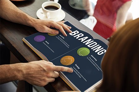 man pointing out branding guidelines in a book