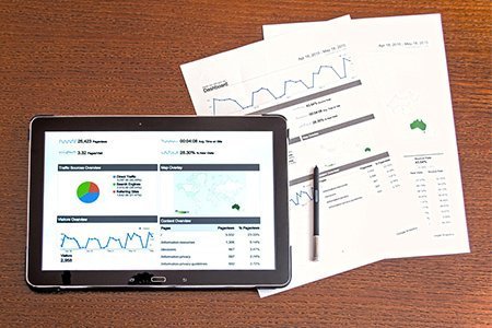 tablet and spreadsheets displaying charts and graphs