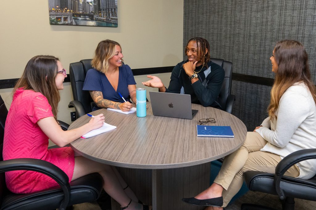 Four marketing professionals discuss a plan while sitting at a round table.