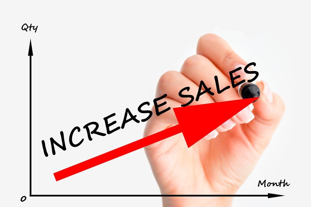 Increase sales graph with a hand holding a pen in the background