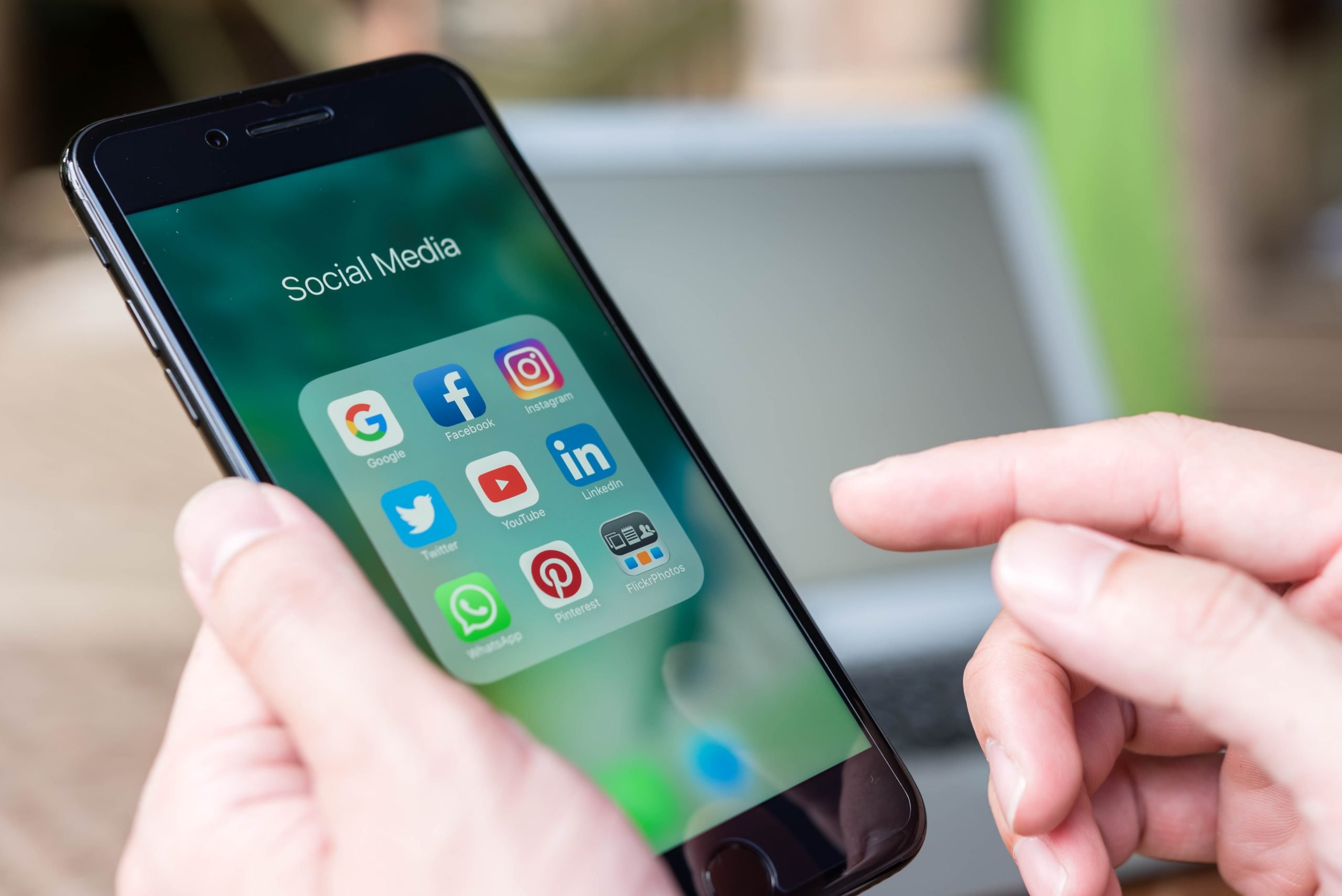 Man's hand holding iPhone smart phone showing social media apps icons