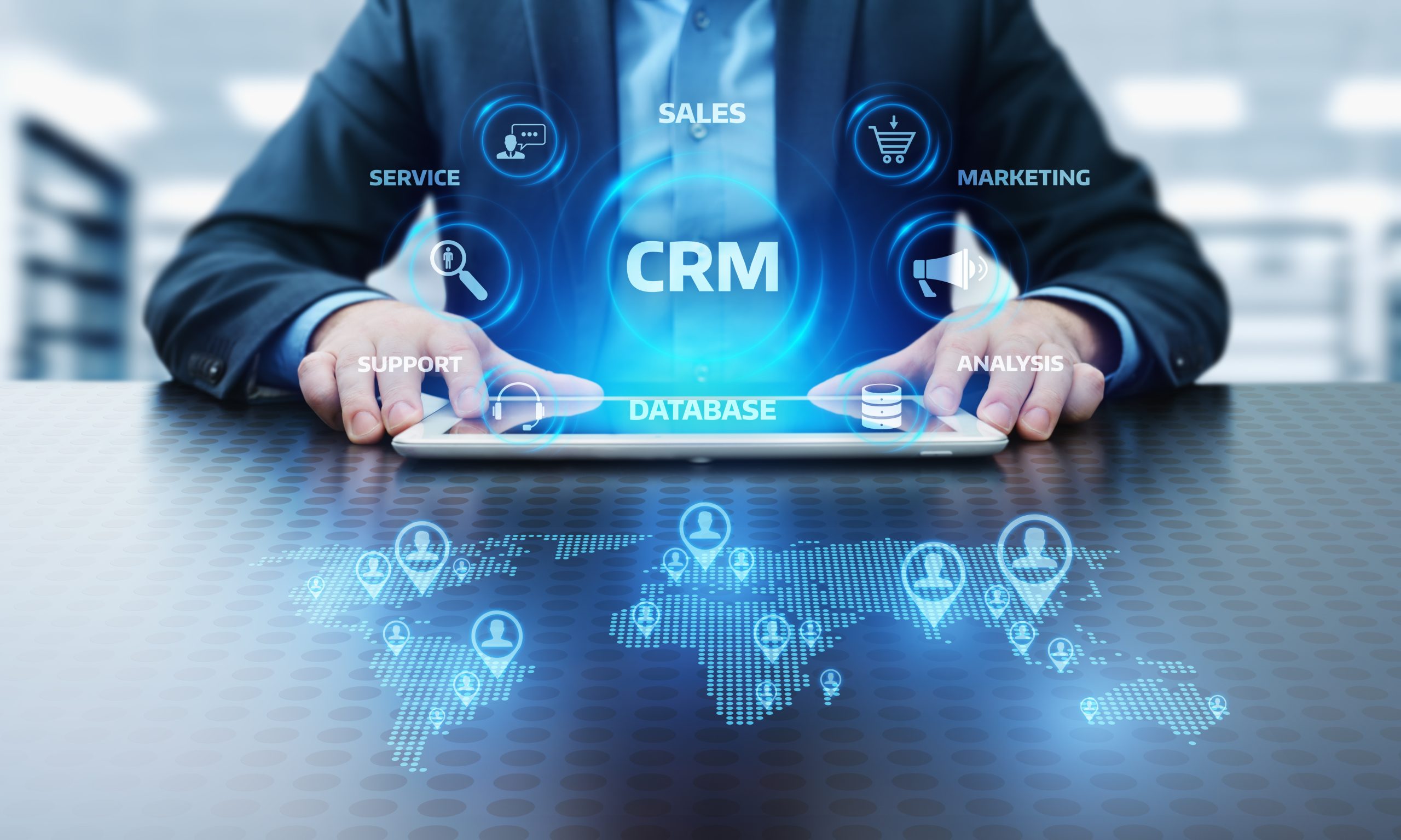 Man touching a tablet with CRM text and icons around on a virtual screen