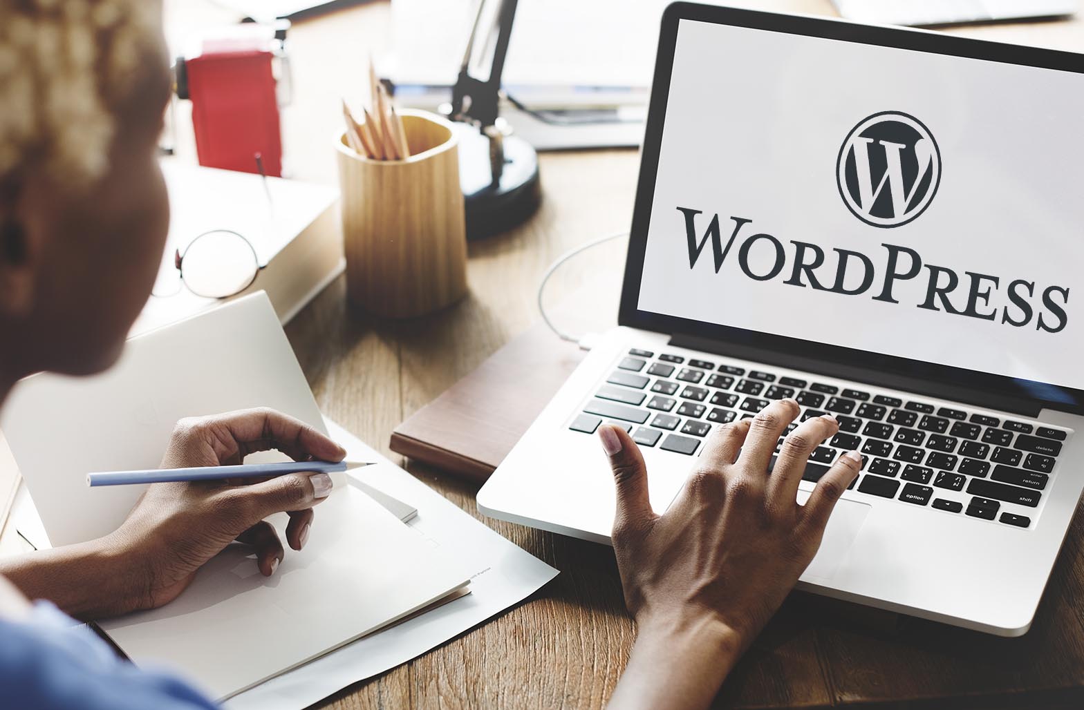 Small Business Owner typing on a laptop with WordPress concept on the screen while writing on a notebook