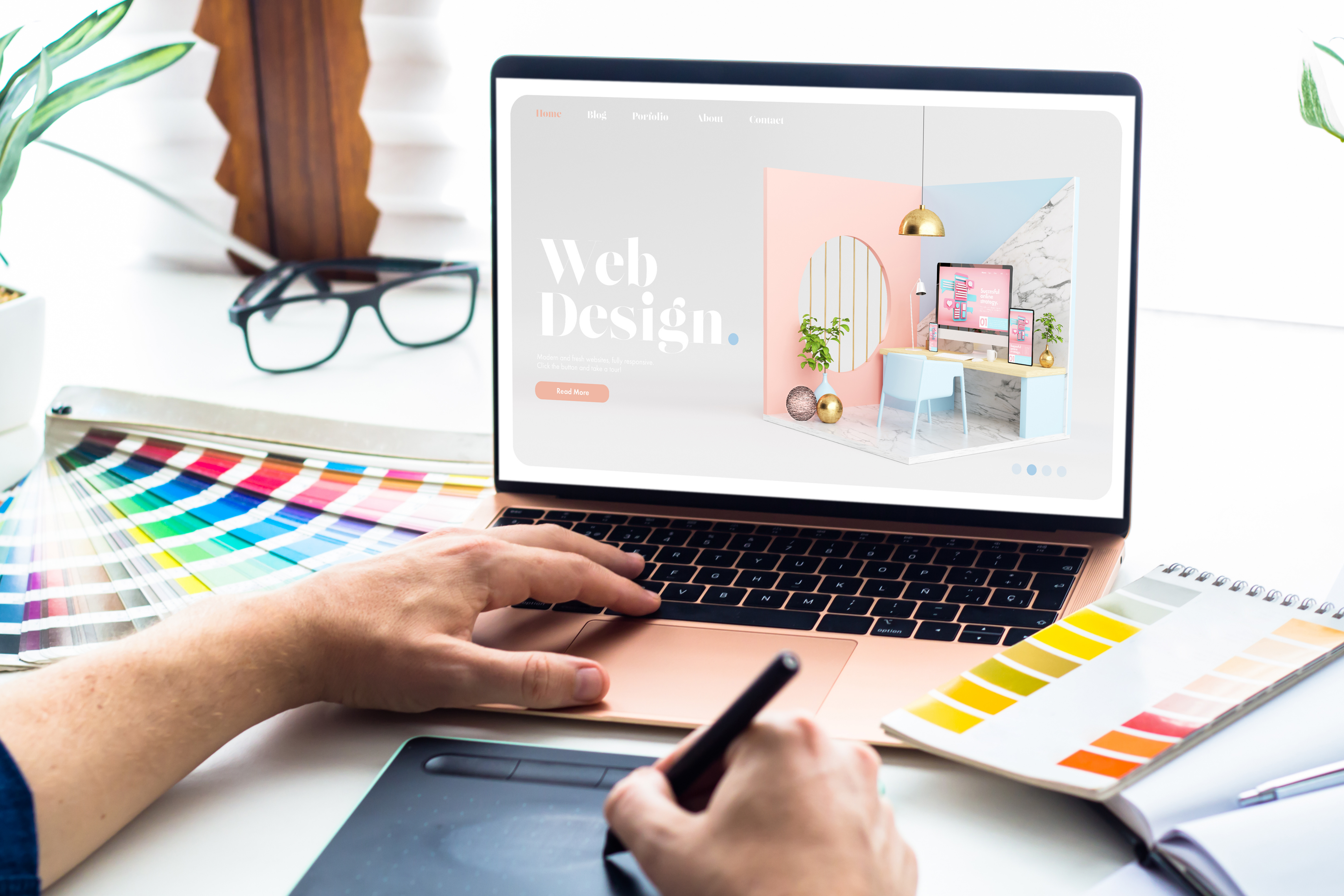 Man drawing on tablet for a web design concept displayed on laptop screen